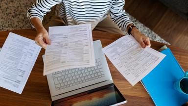 Frau prüft Rechnungen an einem Laptop.