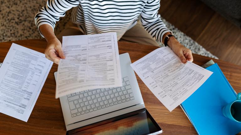 Frau prüft Rechnungen an einem Laptop.