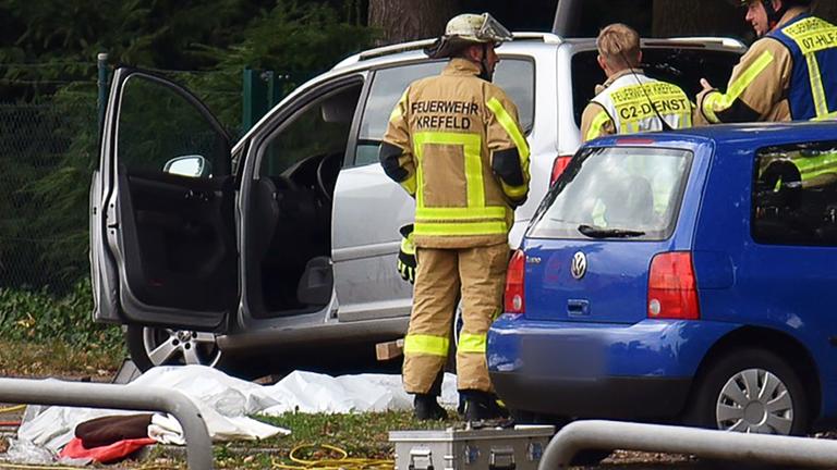  Kräfte der Feuerwehr sind am Friedhof Gellep-Stratum an der Unfallstelle im Einsatz. Auf dem Parkplatz des Friedhofs ist ein Auto in eine Menschenmenge gefahren.