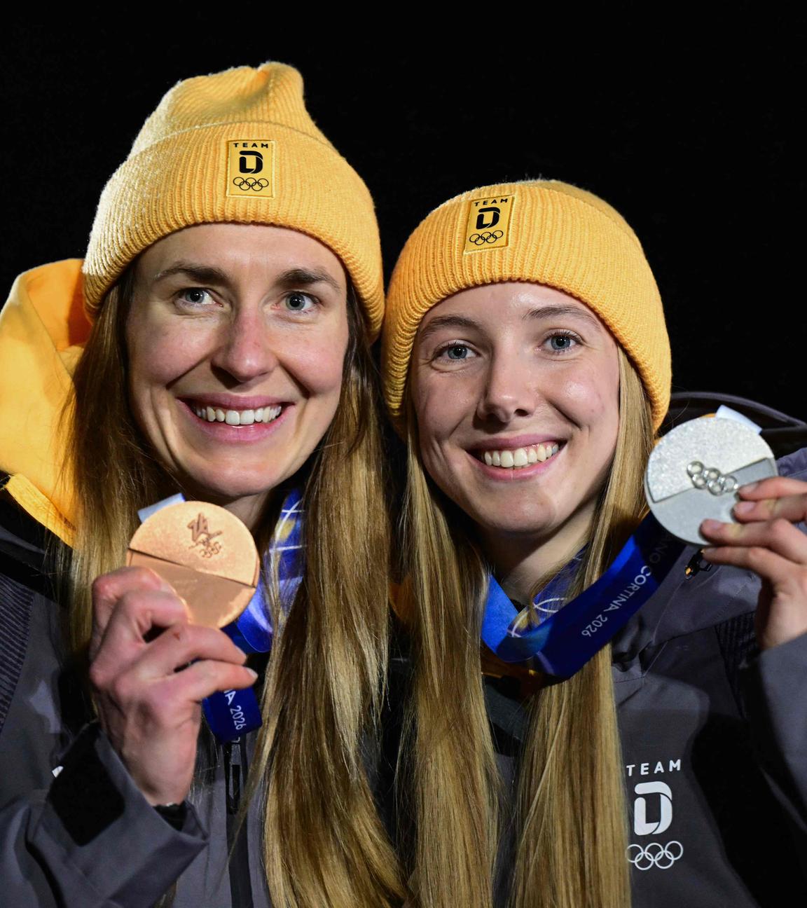 Die deutschen Skeletonpilotinnen Jacqueline Pfeifer und Susanne Kreher präsentieren ihre beiden Medaillen bei den Olympischen Winterspielen 2026 in Cortina