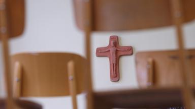 Ein Kreuz hängt in einem Klassenzimmer der Grundschule in Kaufbeuren, Schwaben, hinter auf Schulbänken gestellten Stühle am 27.04.2010. 
