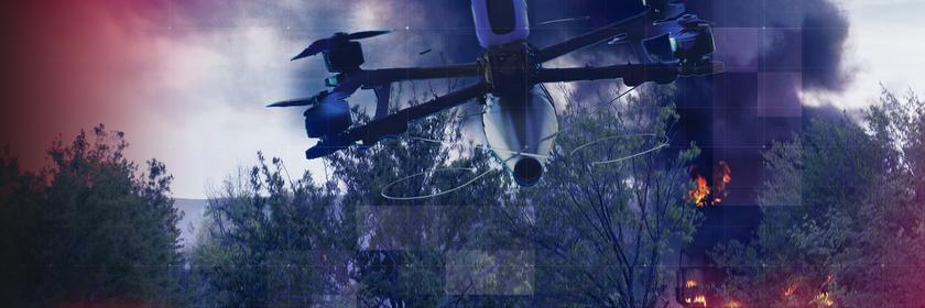 Montage: FPV-Drohne vor brennendem Militärfahrzeug im Unterholz eines Wald- und Wiesengebietes