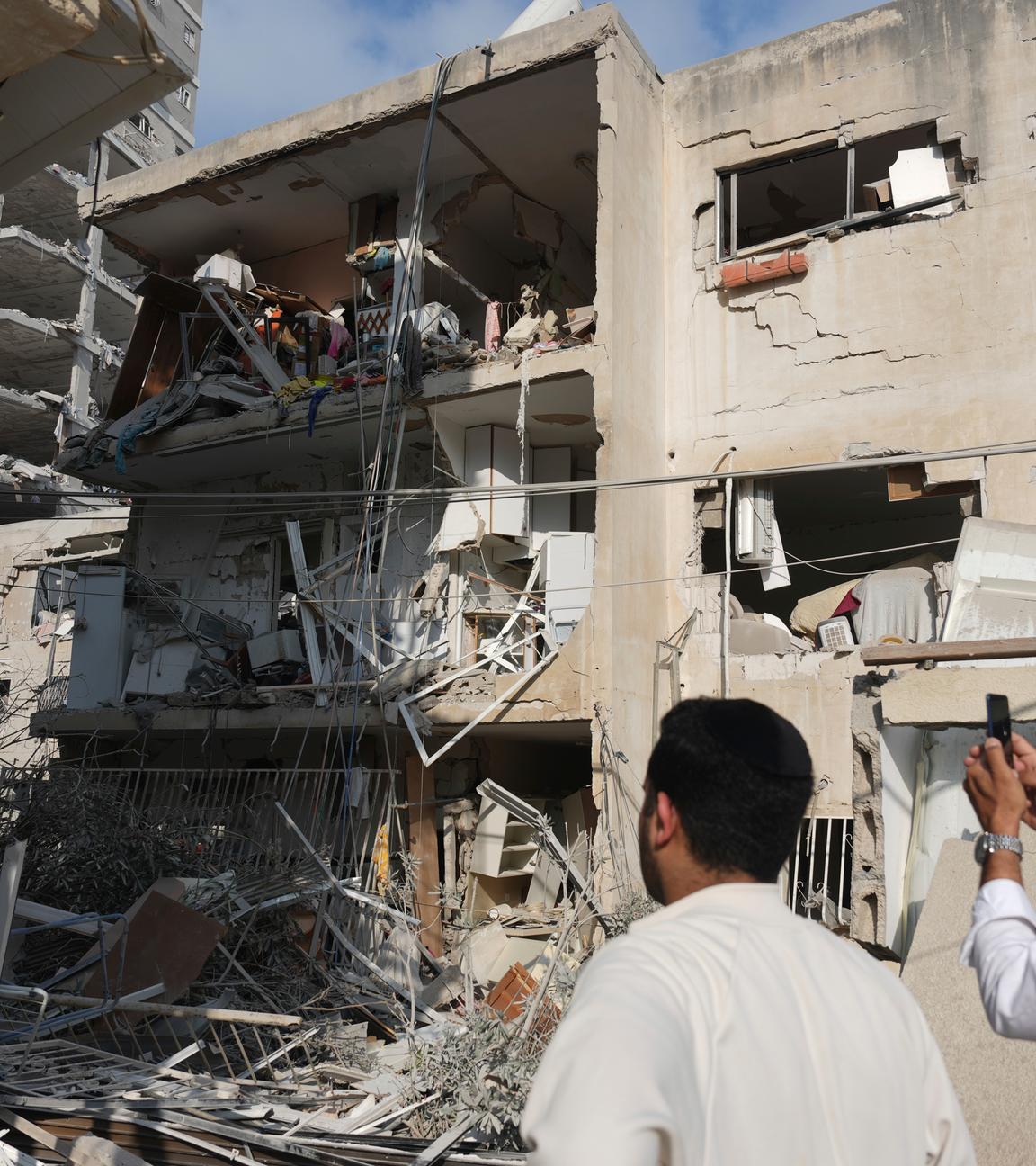 Menschen inspizieren ein zerstörtes Gebäude, das von einer aus dem Iran abgefeuerten Rakete getroffen wurde, in der Nähe von Tel Aviv, Israel.