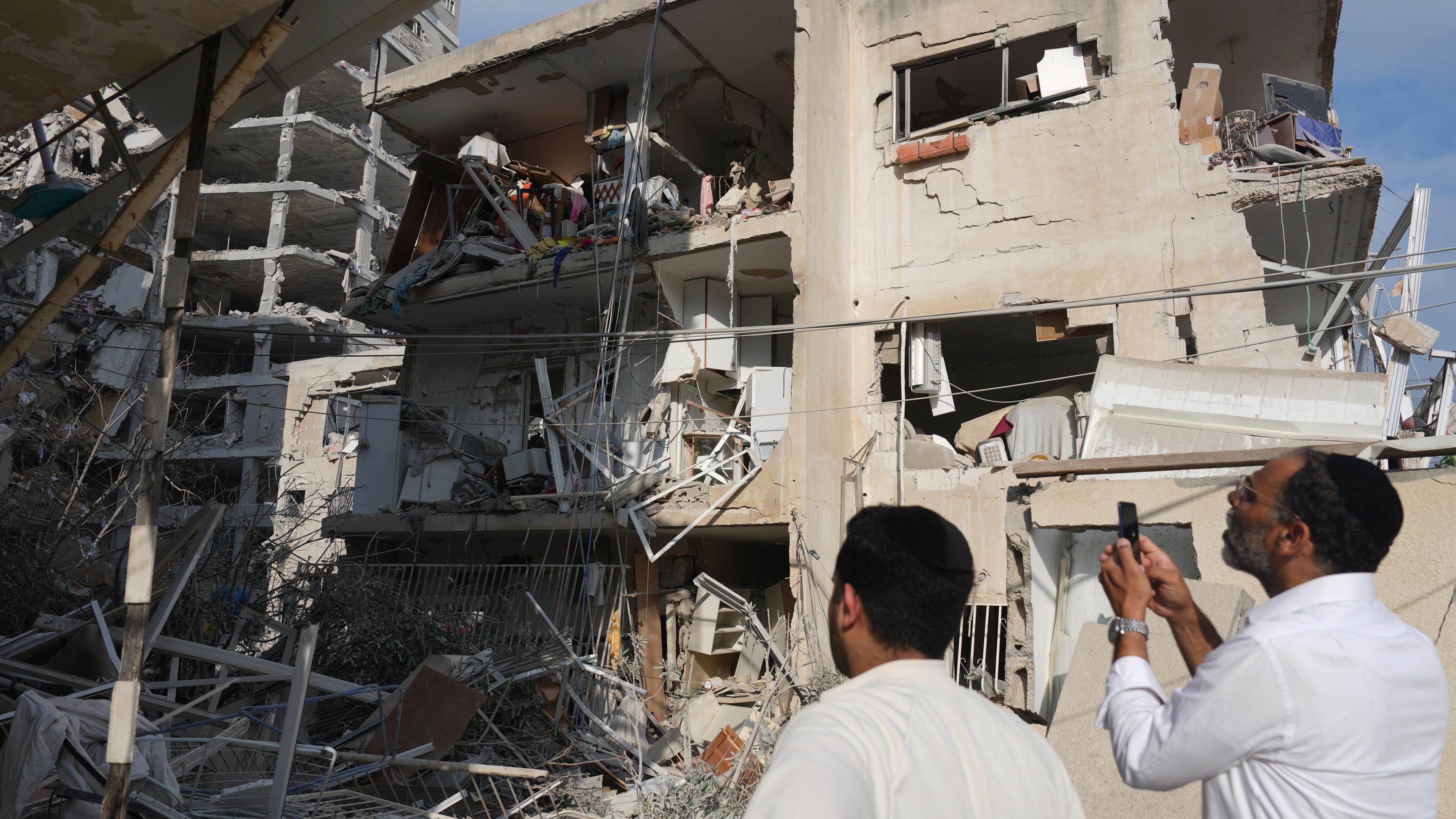 Menschen inspizieren ein zerstörtes Gebäude, das von einer aus dem Iran abgefeuerten Rakete getroffen wurde, in der Nähe von Tel Aviv, Israel.