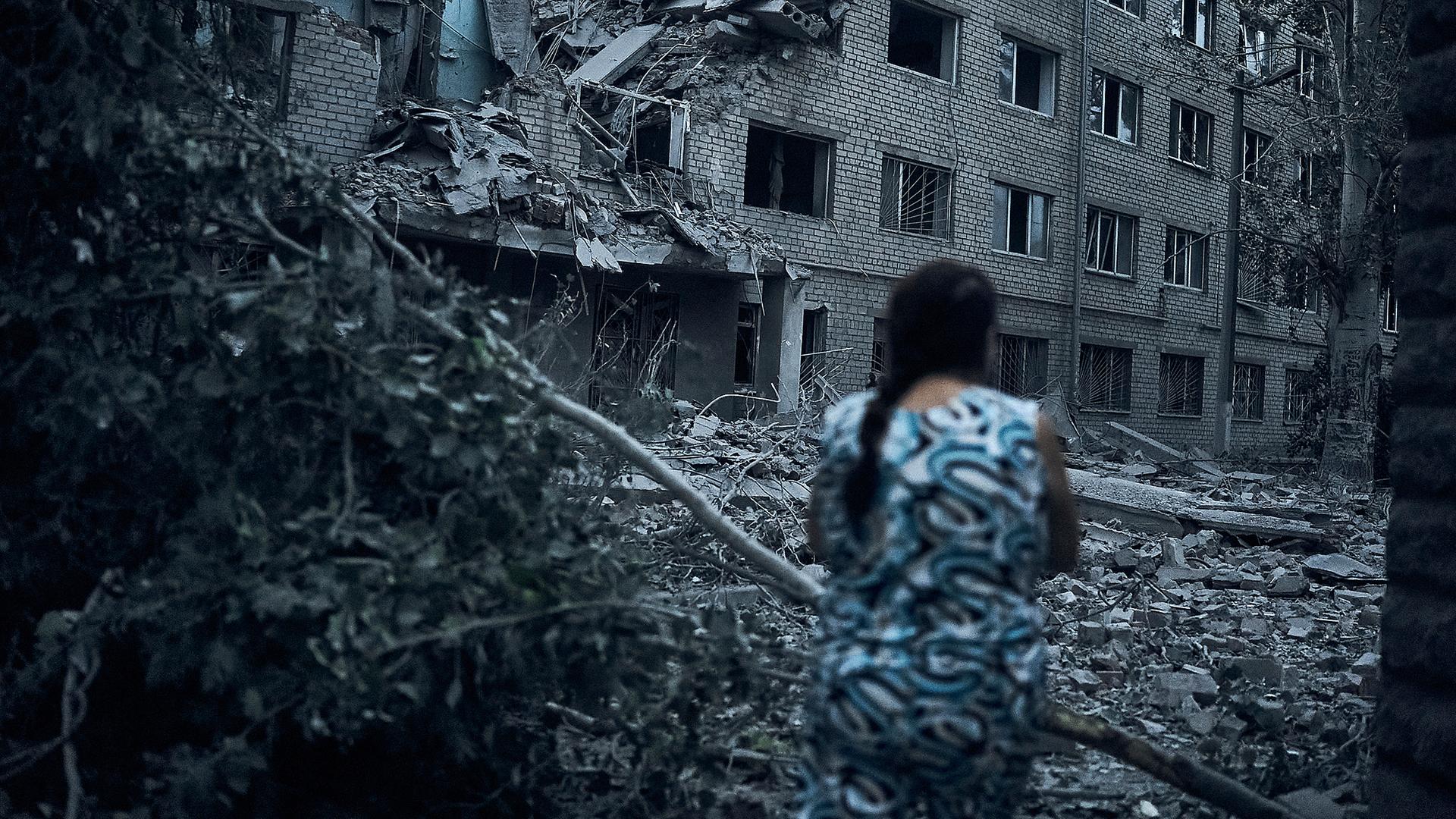 Eine ukrainische Frau geht inmitten der Trümmer eines Wohnhauses nach nächtlichem Beschuss in Mykolaiv (Ukraine), aufgenommen am 02.08.2022