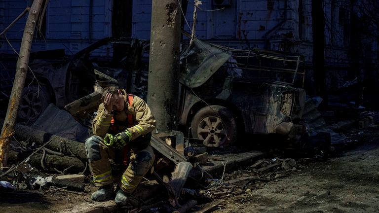 Ein Rettungssanitäter ruht in der Nähe eines Universitätsgebäudes, das durch einen russischen Raketenangriff auf Sumy (Ukraine) zerstört wurde, 13. April 2025.