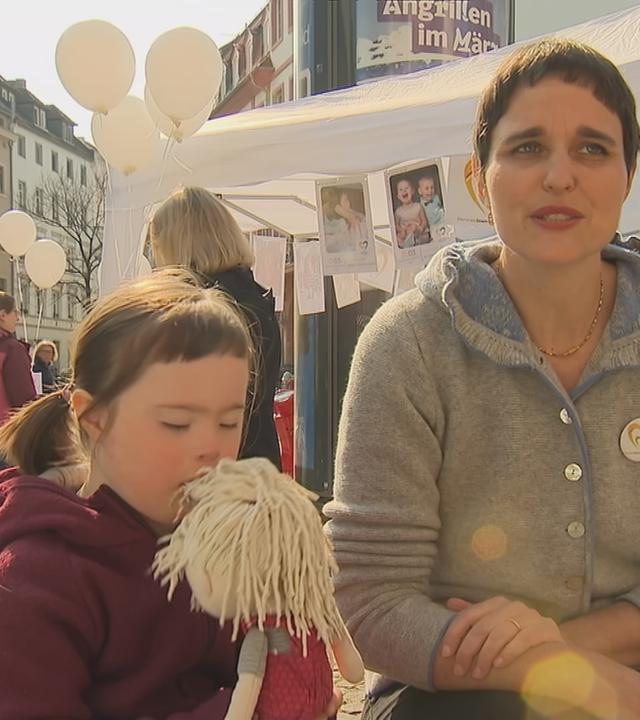 Mutter auf einer Veranstaltung mit Tochter mit Trisomie 21