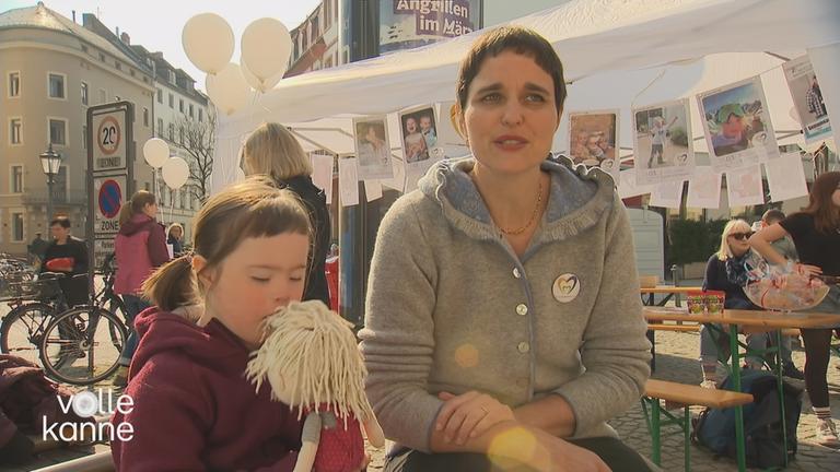 Mutter auf einer Veranstaltung mit Tochter mit Trisomie 21