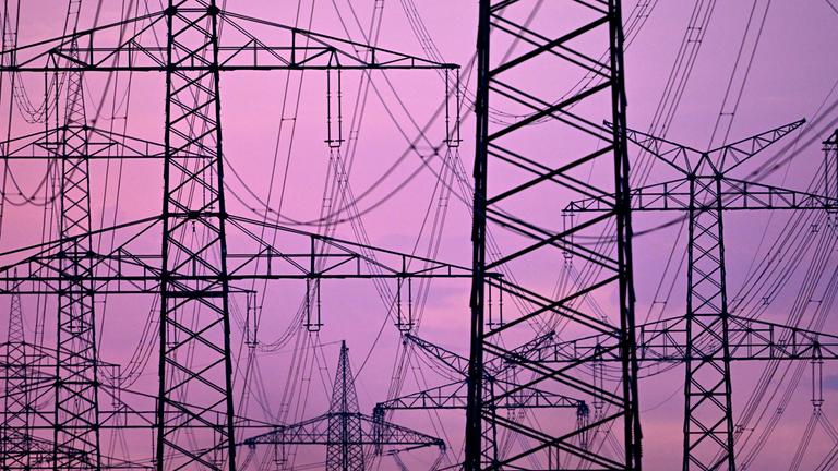 Strommasten stehen in der Dämmerung am Morgen auf einem Feld.