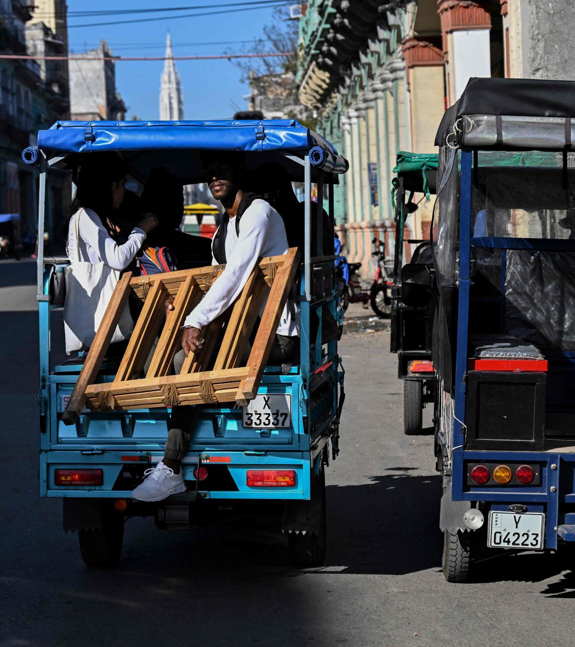 Menschen fahren in einem elektrischen Dreirad durch die Straßen von Havanna, Kuba.
