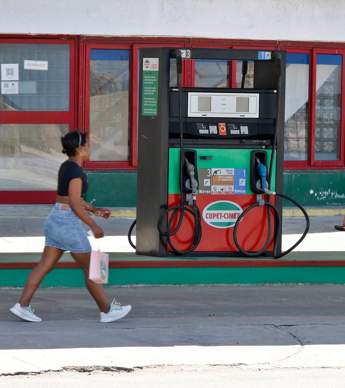 Kuba: Eine Frau an einer leeren Tankstelle in Havana. 