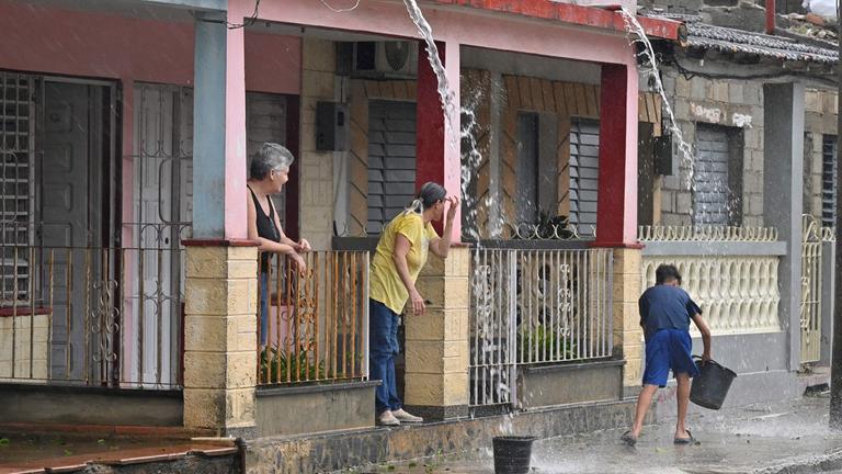 Menschen in Kuba schippen das Regenwasser