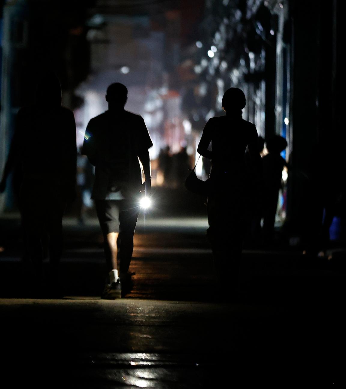 Menschen laufen im Dunkeln die Straße hinunter in Havana, Cuba, nachdem zum zweiten Mal binnen einer Woche landesweit der Strom ausgefallen ist.