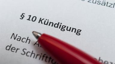 Ein roter Kugelschreiber auf einem Papierdokument. Darauf lesbar "§10 Kündigung"