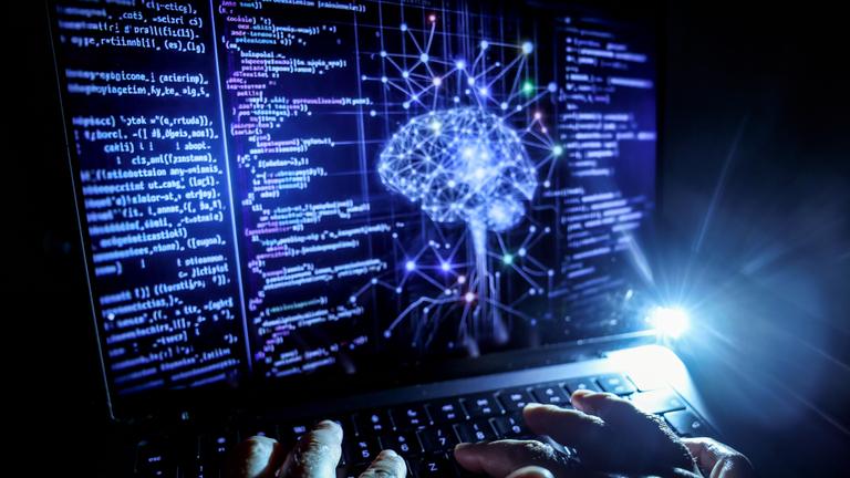 KI Symboldbild: Gehirn auf Bildschirm mit Prammier-Codes