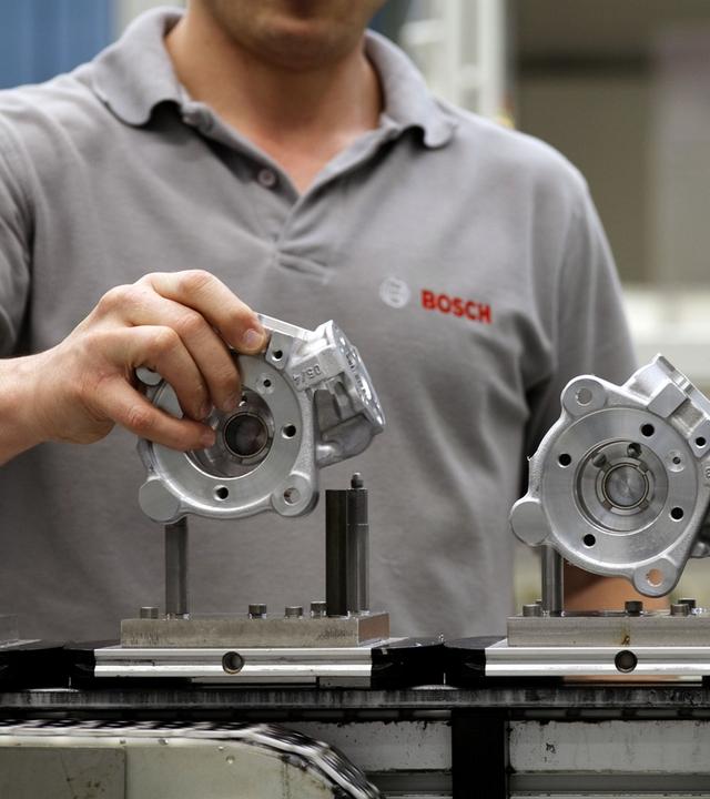 Ein Mitarbeiter von Bosch bringt bei der Produktion von Dieseleinspritzpumpen ein Bauteil in Position. 