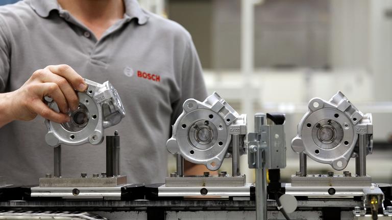 Ein Mitarbeiter von Bosch bringt bei der Produktion von Dieseleinspritzpumpen ein Bauteil in Position. 