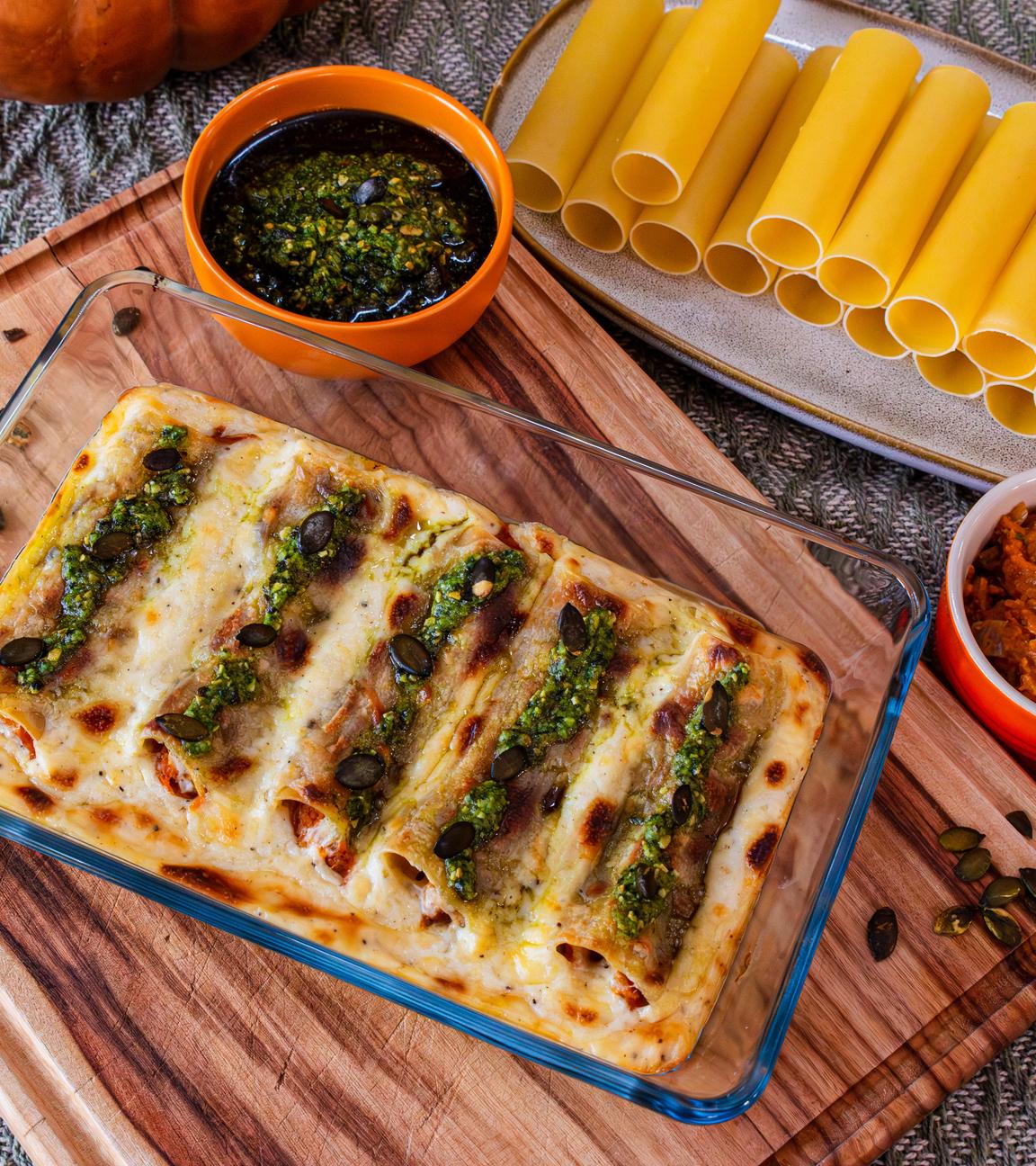 Kürbis-Cannelloni in einer Schale, daneben zwei Schälchen mit Saucen, darunter Pesto.