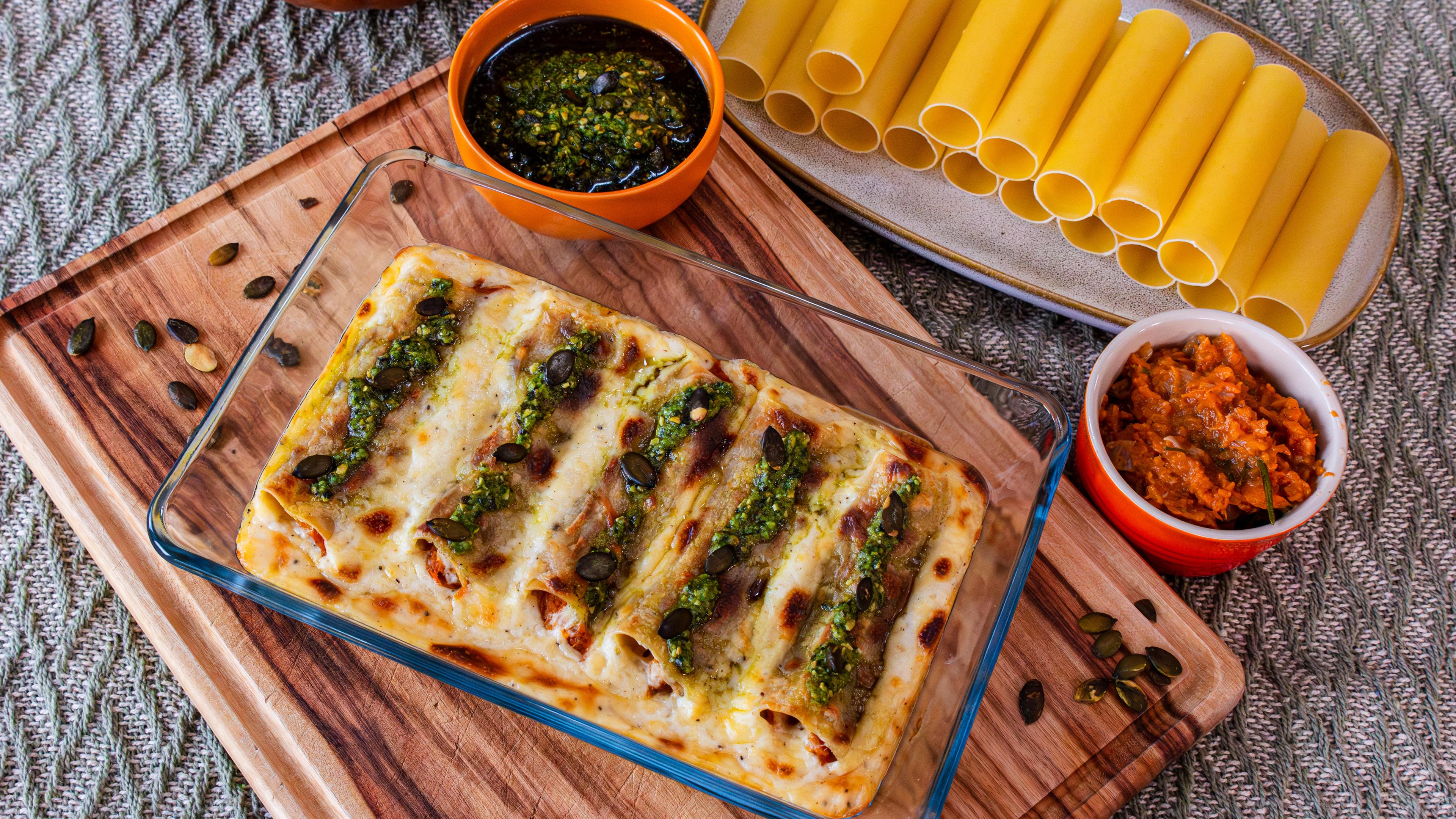 Kürbis-Cannelloni in einer Schale, daneben zwei Schälchen mit Saucen, darunter Pesto.