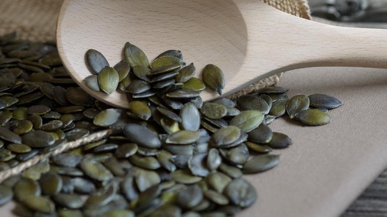 Kürbiskerne auf einem Holzlöffel.