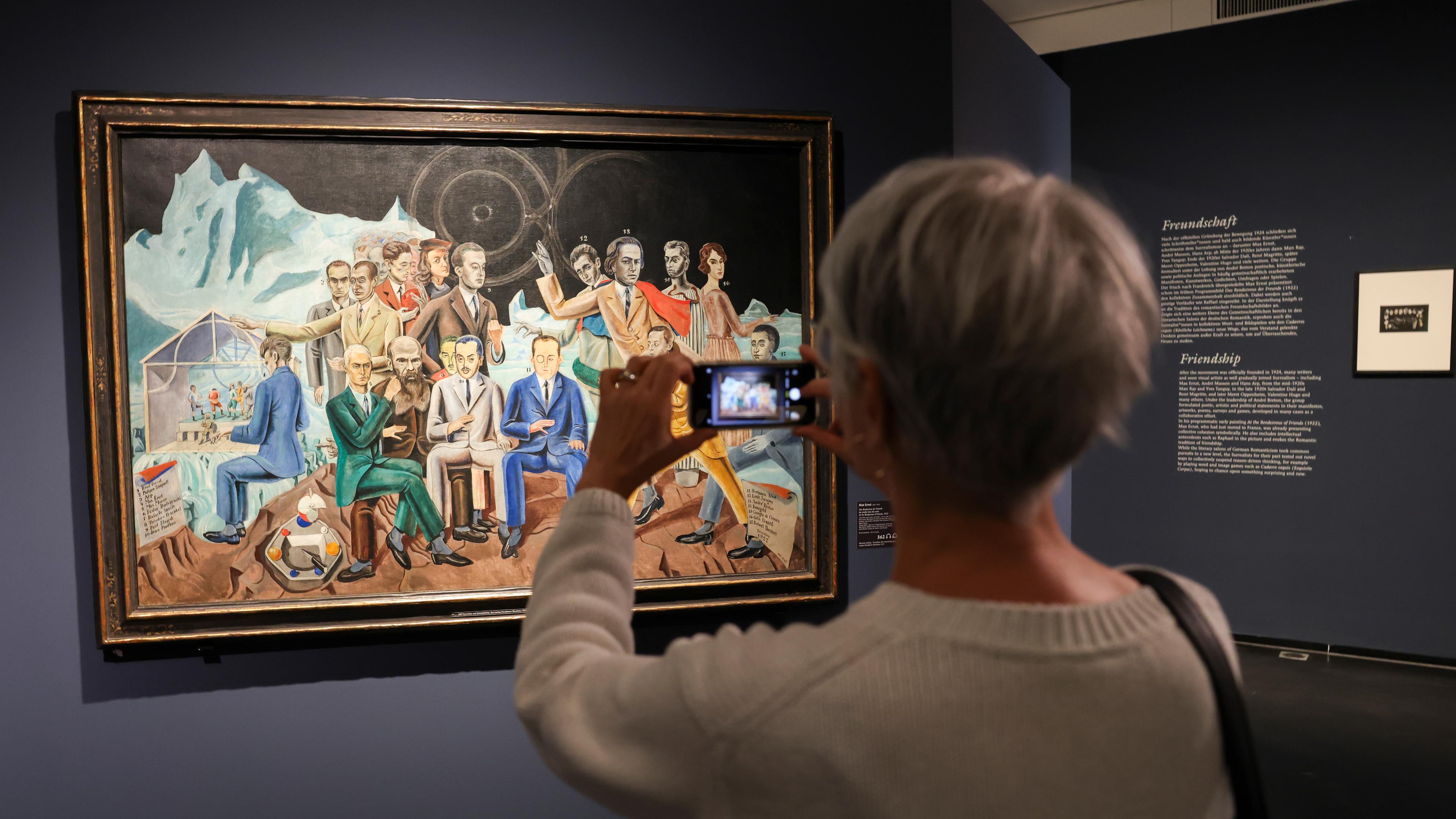 Eine Besucherin fotografiert das Bild "Das Rendezvous der Freunde" (1922) von Max Ernst beim Eröffnungsrundgang in der Hamburger Kunsthalle in der Ausstellung "Rendezvous der Träume - Surrealismus und deutsche Romantik".