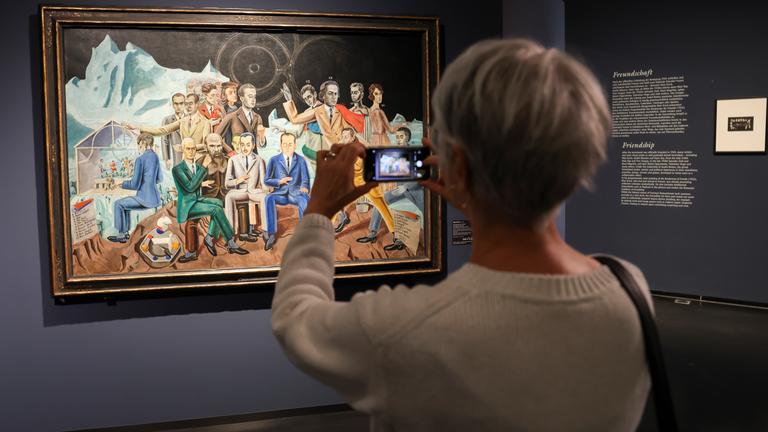Eine Besucherin fotografiert das Bild "Das Rendezvous der Freunde" (1922) von Max Ernst beim Eröffnungsrundgang in der Hamburger Kunsthalle in der Ausstellung "Rendezvous der Träume - Surrealismus und deutsche Romantik".