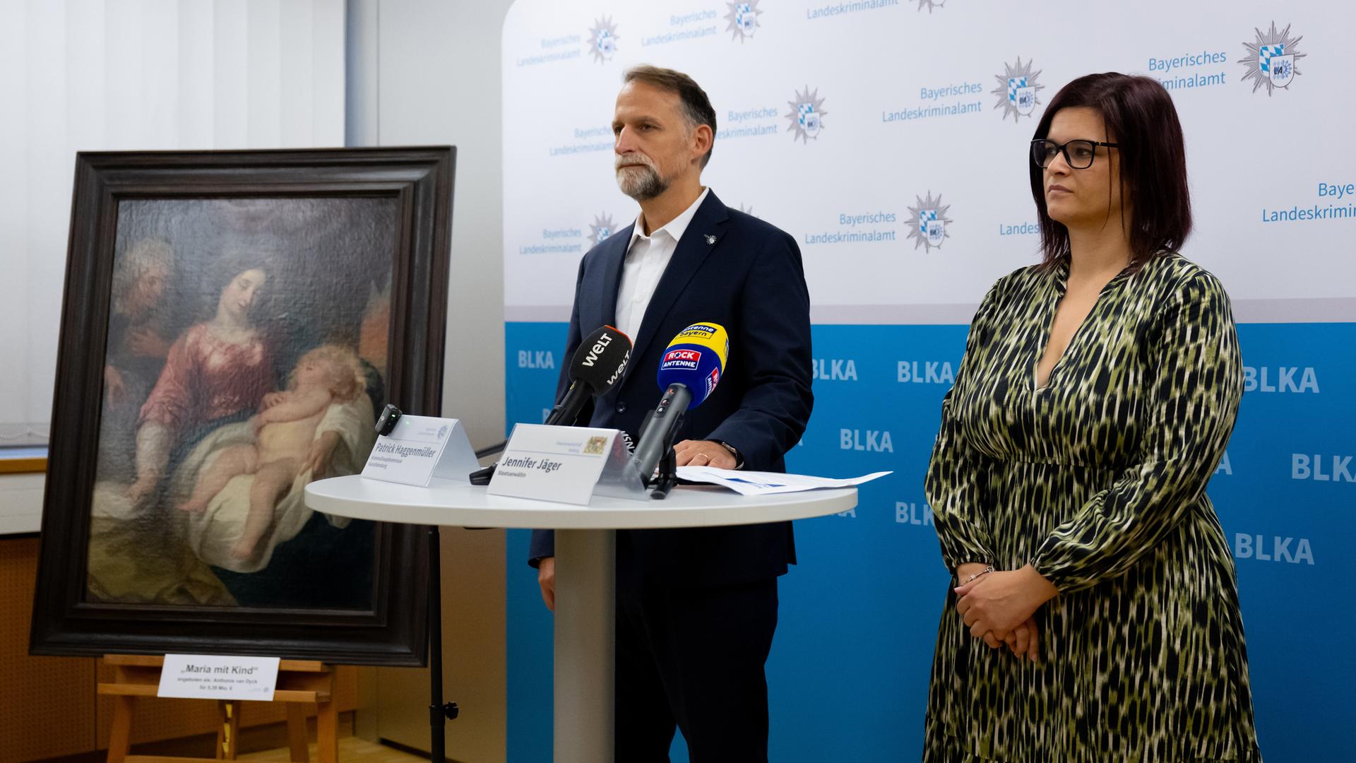 Jennifer Jäger, Staatsanwältin, und Patrick Haggenmüller, Leiter der Kunstfahndung des Bayerischen Landeskriminalamtes (BLKA) und Hauptsachbearbeiter, nehmen an einer Pressekonferenz teil und stehen neben dem gefälschten Bild Maria mit Kind, angeboten als Anthonis van Dyck für 5,39 Millionen Euro.
