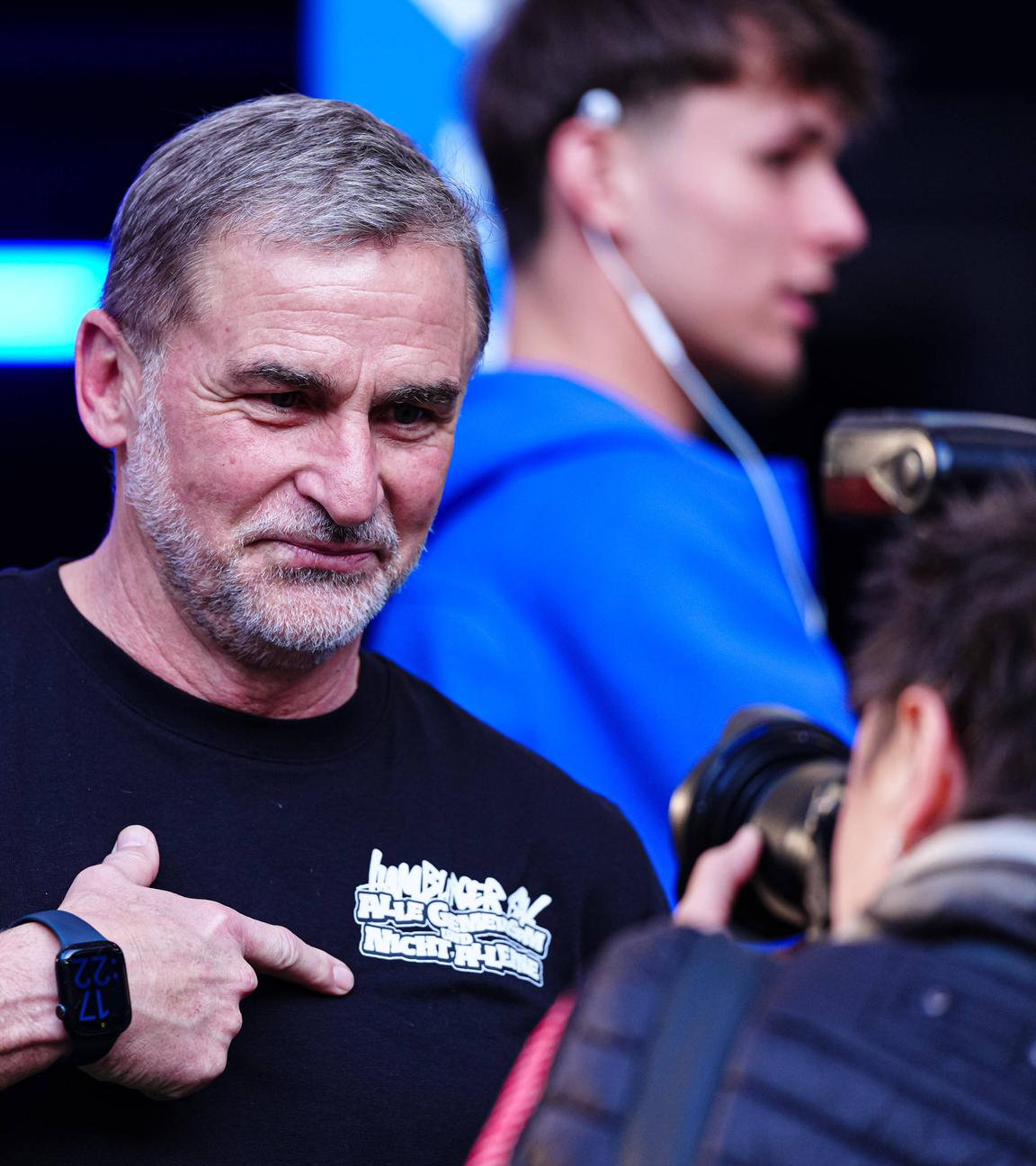 Stefan Kuntz deutet auf den Schriftzug auf seinem T-Shirt