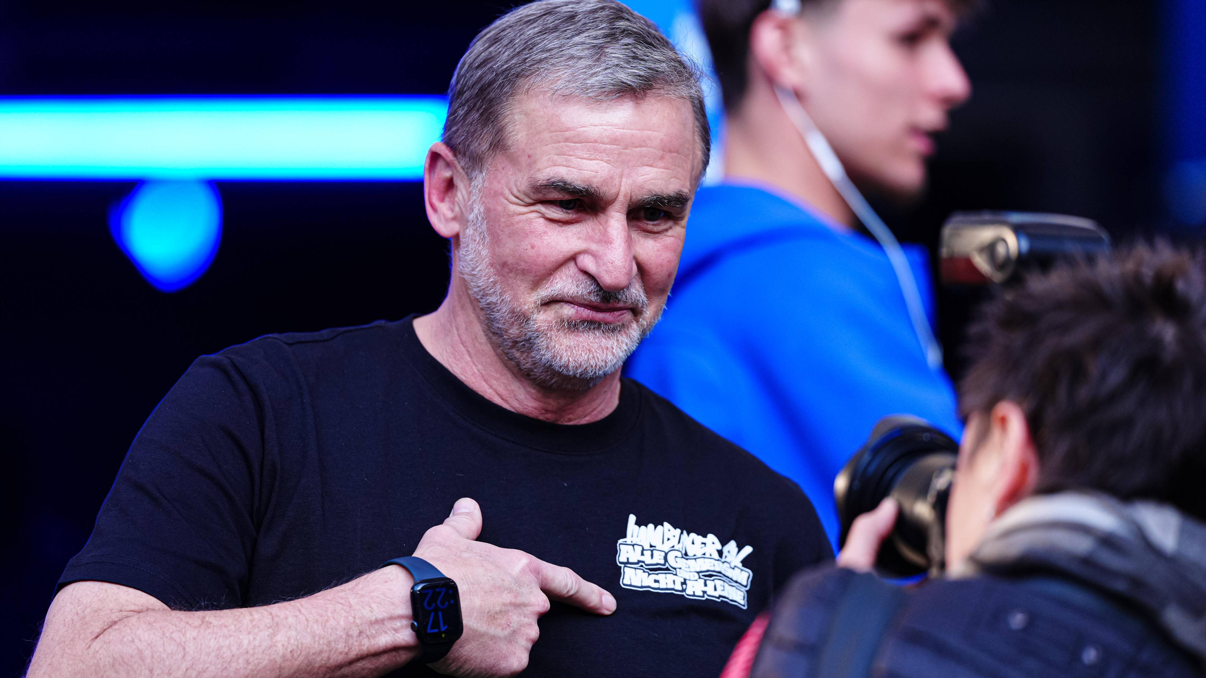 Stefan Kuntz deutet auf den Schriftzug auf seinem T-Shirt