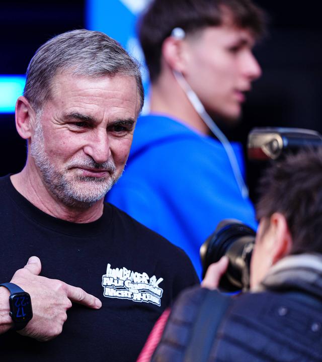 Stefan Kuntz deutet auf den Schriftzug auf seinem T-Shirt