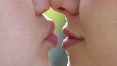 Zwei Gesichter sehr nah, die Nasen stoßen aneinander, die Lippen berühren sich fast.
