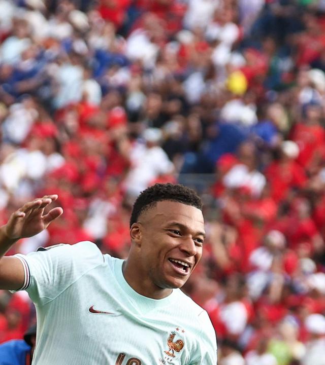 Fußballspieler Kylian Mbappé lachend auf dem Fußballfeld