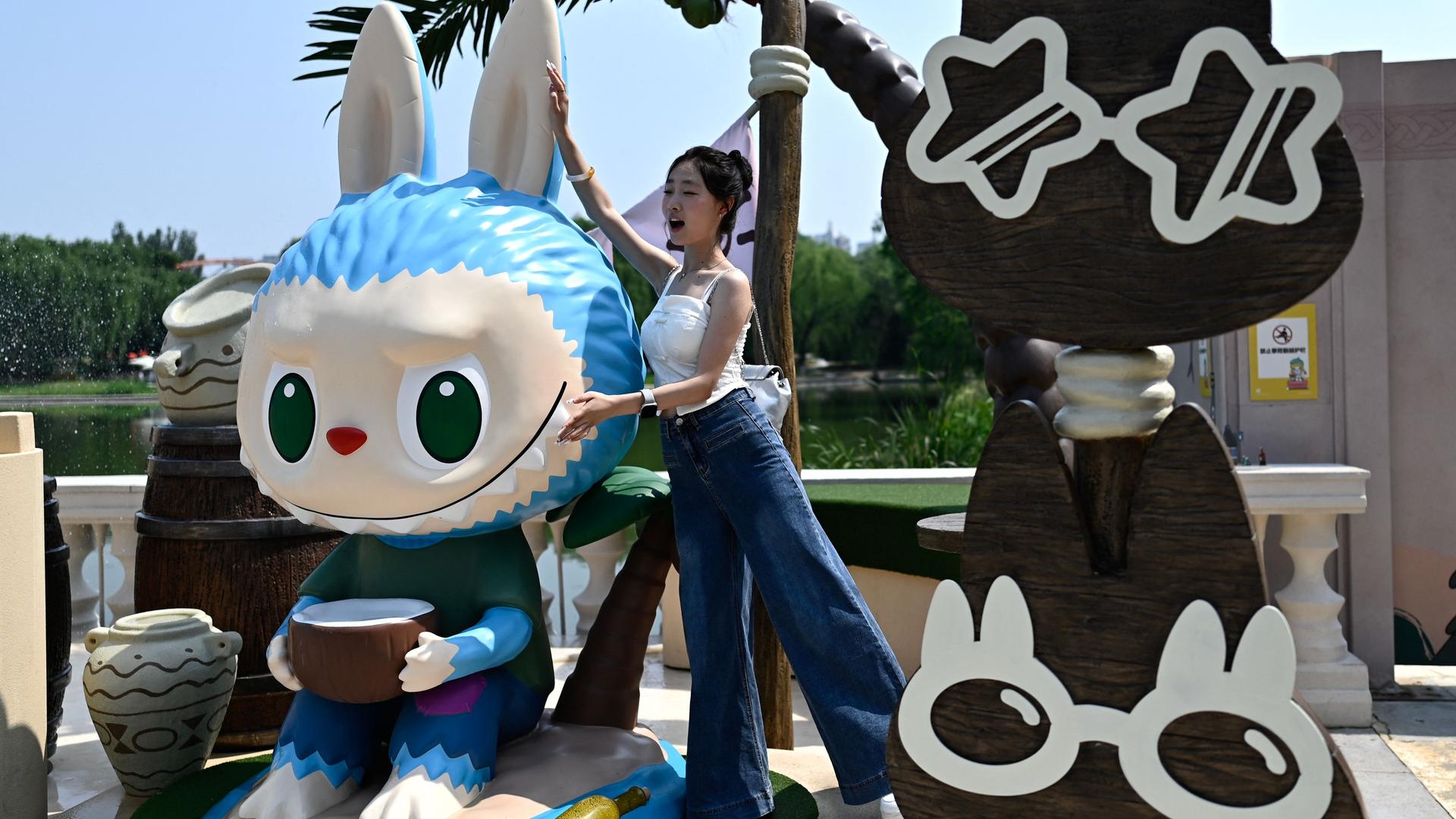 Eine Frau posiert neben einer lebensgroßen Labubu