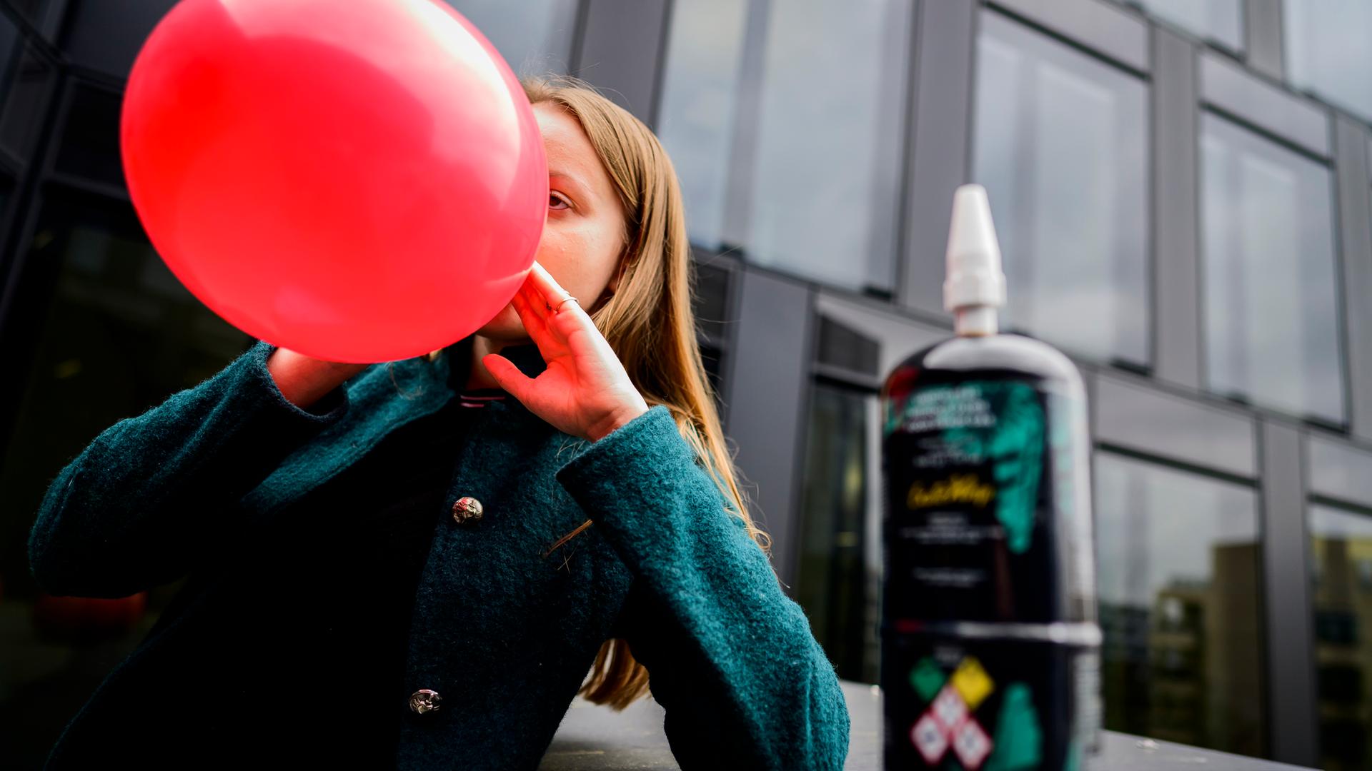 Ein Mädchen atmet die Luft aus einem Luftballon ein