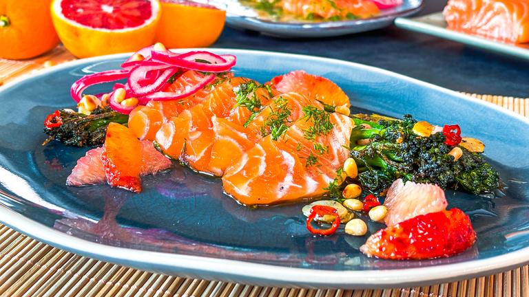 Lachs Crudo mit Grapefruit auf einem blauen Teller serviert.