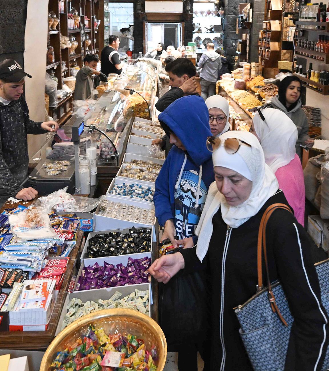 Käufer stöbern am 29.03.2025 in einem Geschäft auf dem überdachten Hamidiya-Markt in Damaskus nach Süßigkeiten