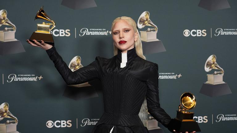 Lady Gaga ist während einer Preisverleihung zu sehen. Sie hält zwei goldene Awards in den Händen.
