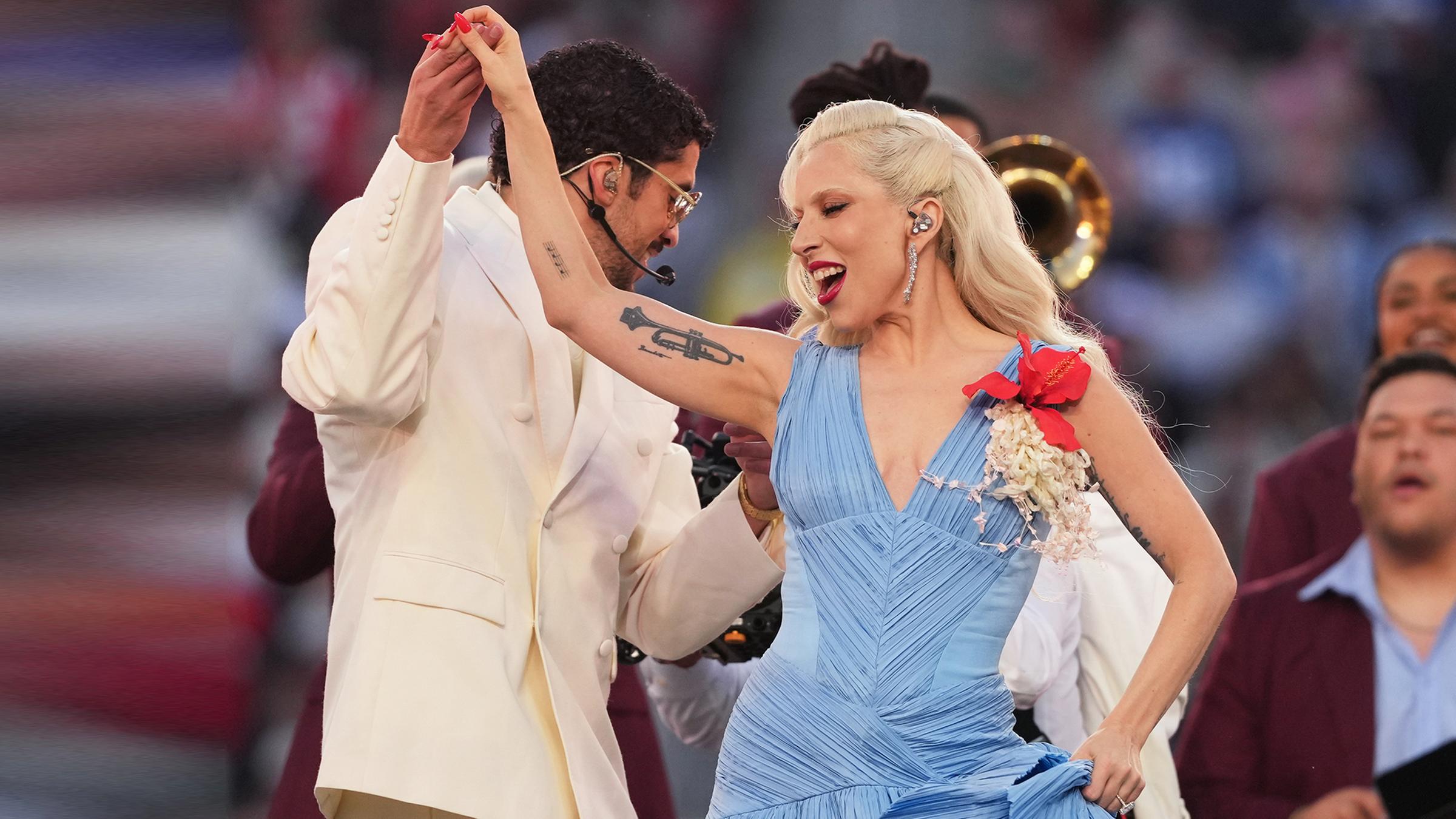 Lady Gaga tritt in der Halbzeitpause beim Superbowl in einem hellblauen Kleid neben Bad Bunny auf. 