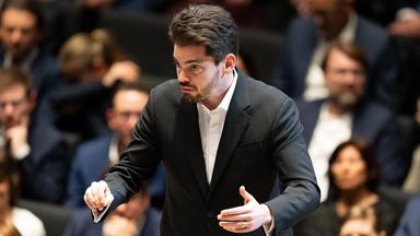 Lahav Shani steht nach der Verleihung der Goldenen Ehrenmünze der Stadt München an Dirigent Mehta auf der Bühne im Januar 2024.