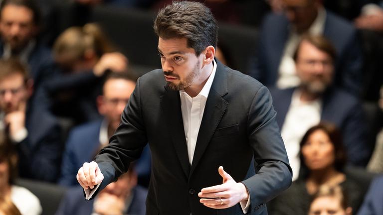 Lahav Shani steht nach der Verleihung der Goldenen Ehrenmünze der Stadt München an Dirigent Mehta auf der Bühne im Januar 2024.