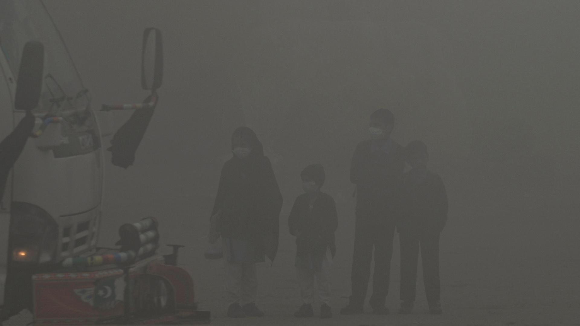 Schulkinder gehen am 14.12.2023 in Lahore inmitten von starkem Smog eine Straße entlang.