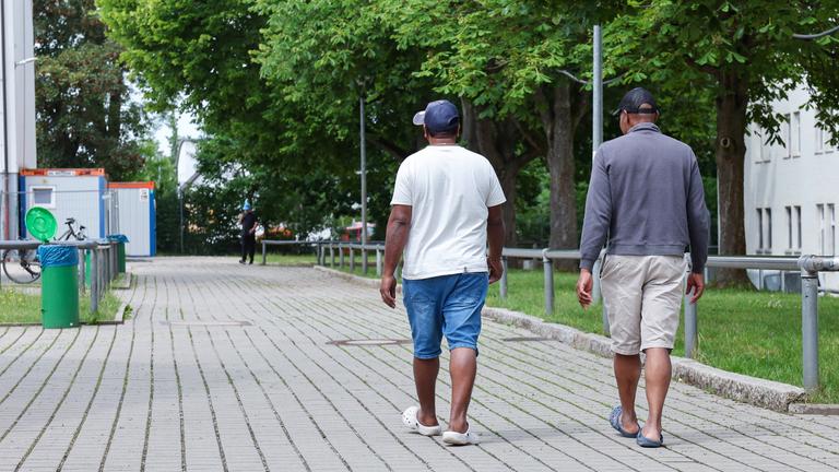 10.06.2025, Bayern, Zirndorf: Zwei Bewohner gehen in der Zentralen Aufnahmeeinrichtung für Asylbewerber in Bayern über das Gelände. 