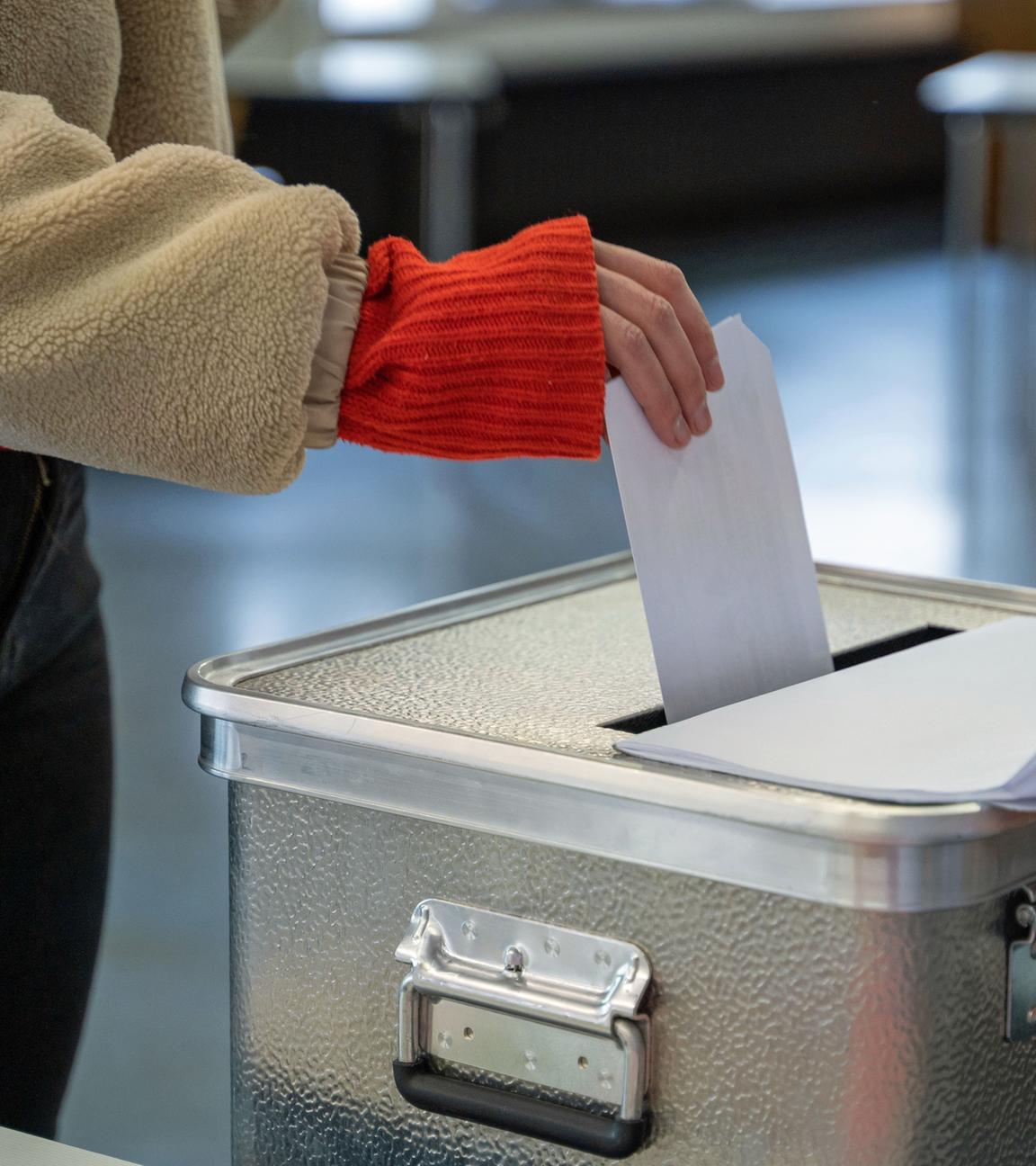 Eine Frau steckt ihren Stimmzettel für die Bundestagswahl in einem Wahllokal in eine Wahlurne.