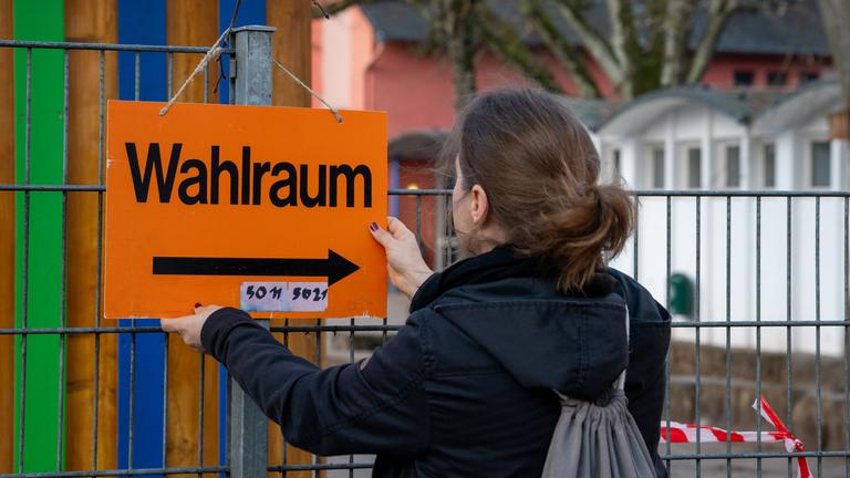 Trier: Wahlbeisitzerin Simone Streit befestigt am Morgen ein Hinweisschild zum Wahlraum. In Rheinland-Pfalz ist heute Landtagswahl.