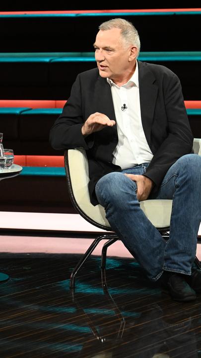 Jan van Aken in Jeans und Jackett, gestikulierend und sitzend bei Markus Lanz.