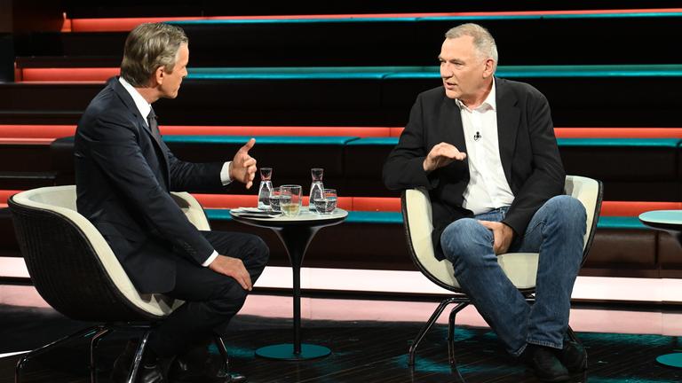 Jan van Aken in Jeans und Jackett, gestikulierend und sitzend bei Markus Lanz.