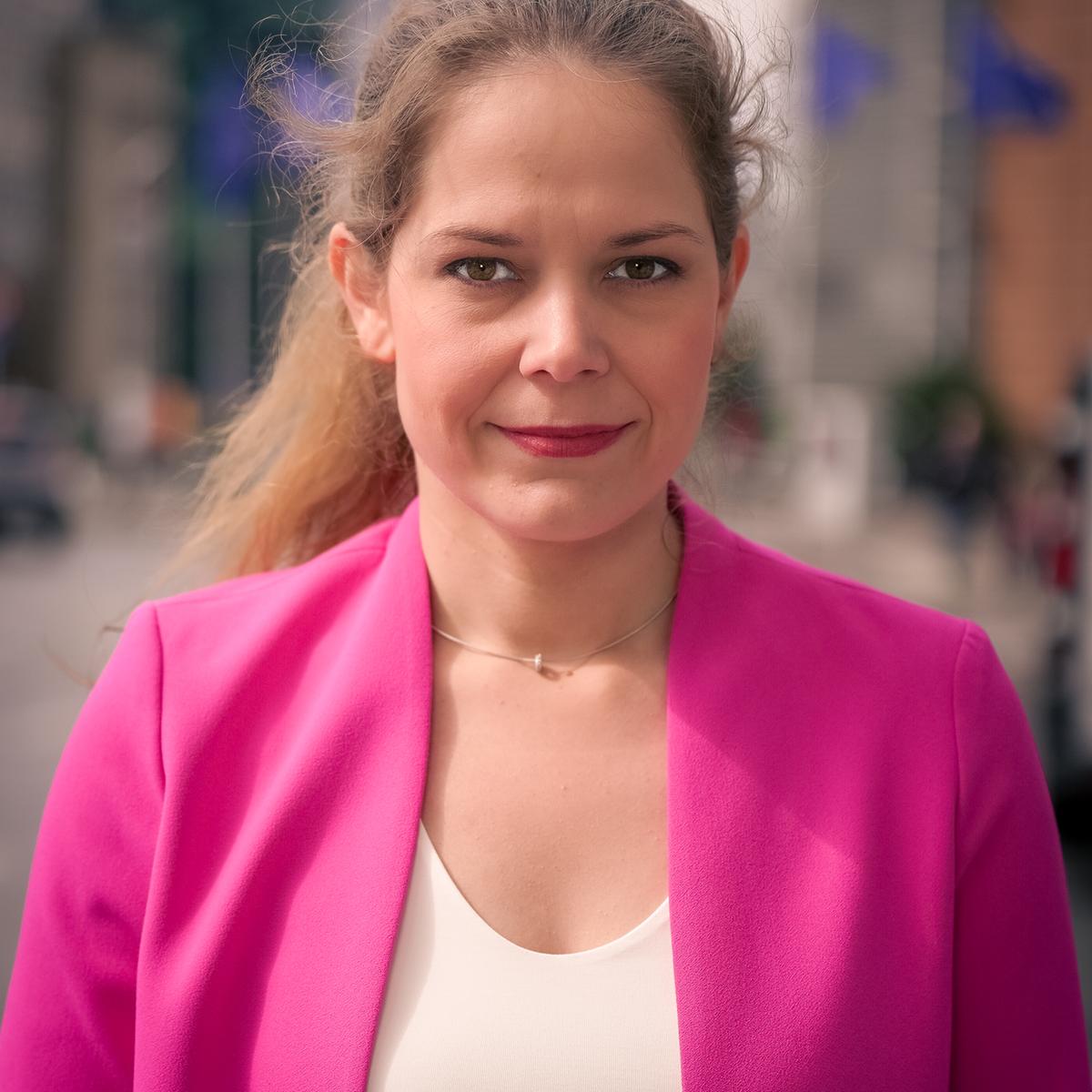 Eine Frau mit braunen Haaren lächelt in die Kamera.