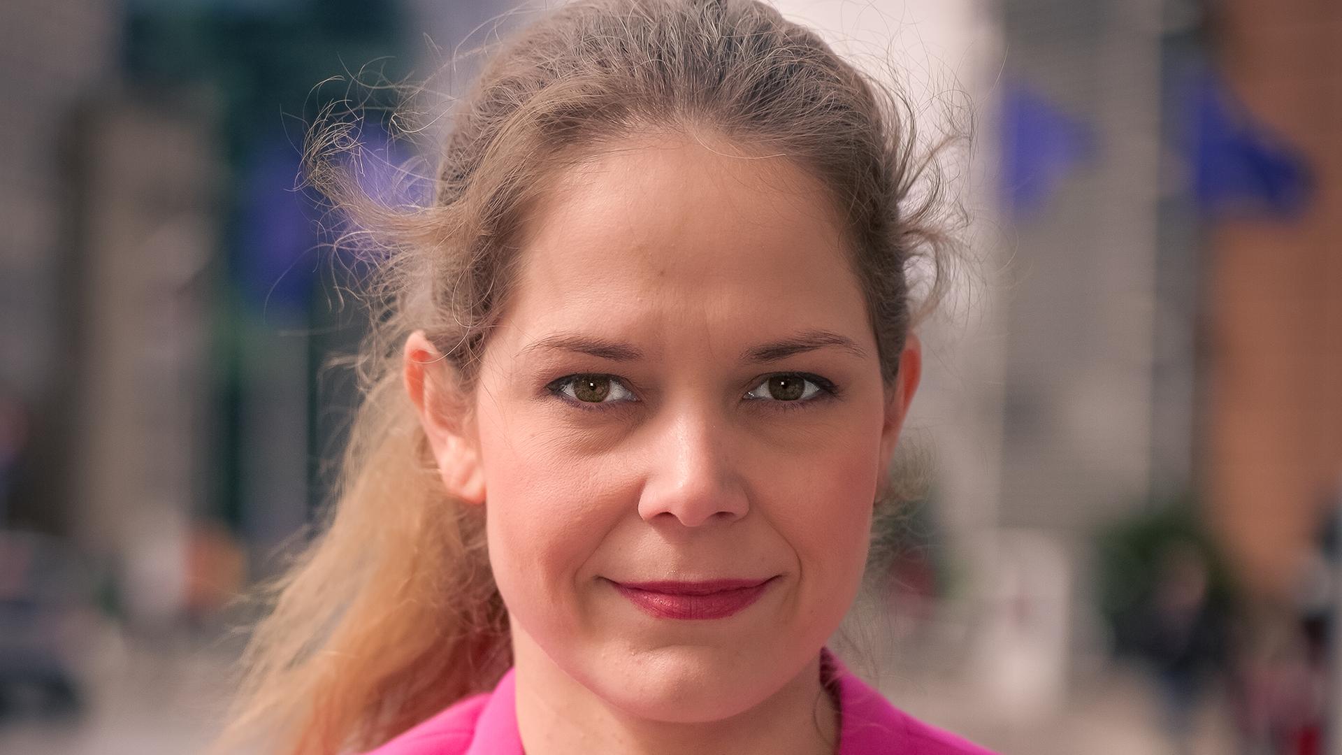 Eine Frau mit braunen Haaren lächelt in die Kamera.