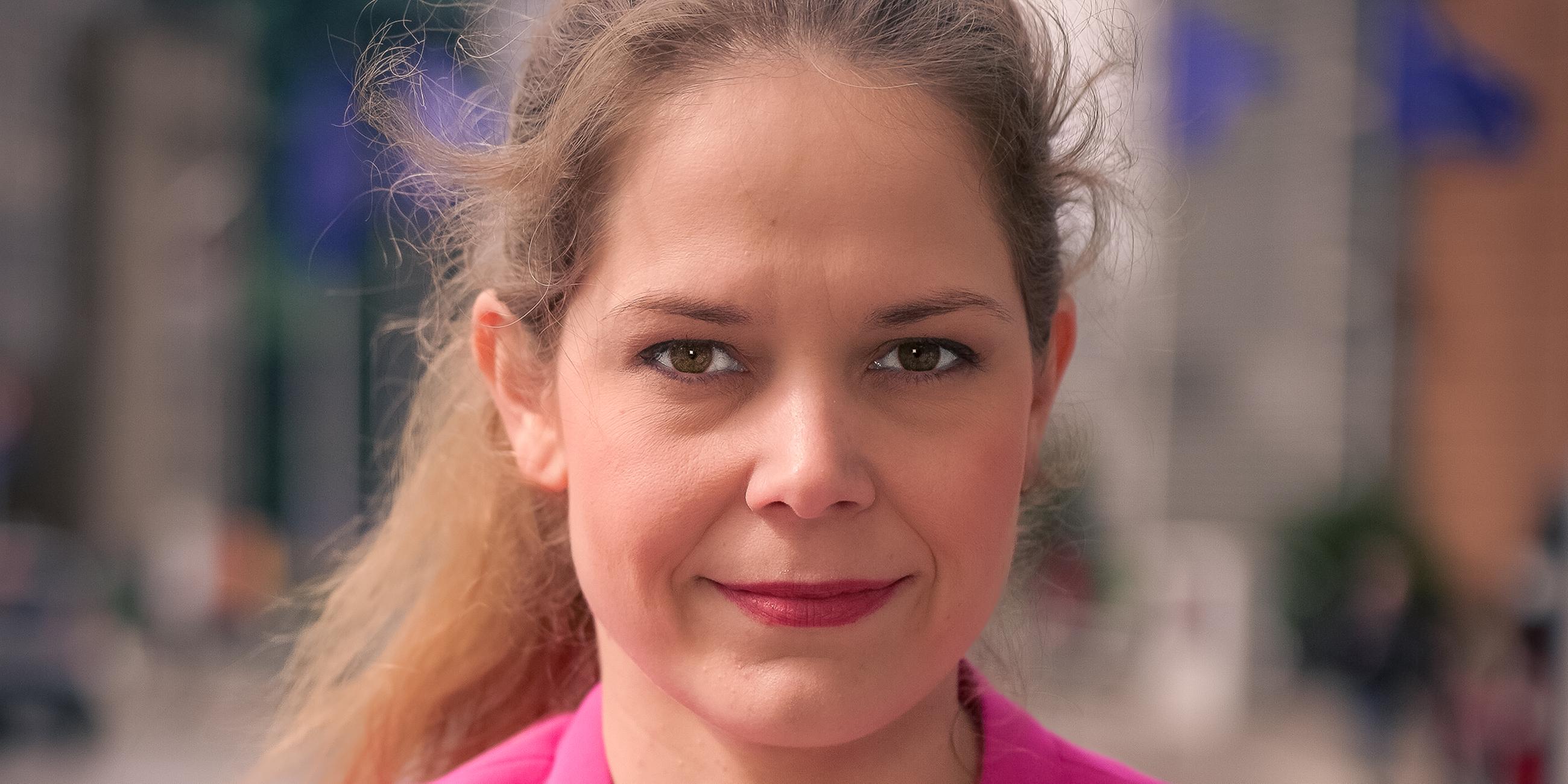 Eine Frau mit braunen Haaren lächelt in die Kamera.