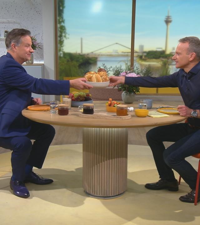 Lars Reichow und Carsten Rüger sitzen am Volle-Kanne-Frühstückstisch und reichen sich den Brotkorb rüber